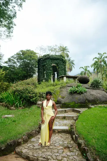 Woman in a yellow dress on stone steps with an ivy-covered arch in the Rio de Janeiro Botanical Garden