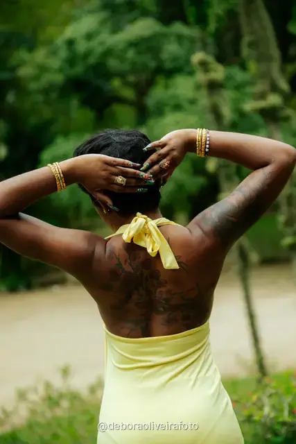 Mujer con vestido amarillo en escalones de piedra con un arco cubierto de hiedra en el Jardín Botánico de Río de Janeiro