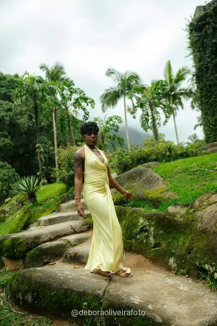 Woman in a yellow dress on stone steps with an ivy-covered arch in the Rio de Janeiro Botanical Garden