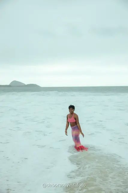 Woman in a pink crochet set on Ipanema Beach with the Two Brothers mountain behind