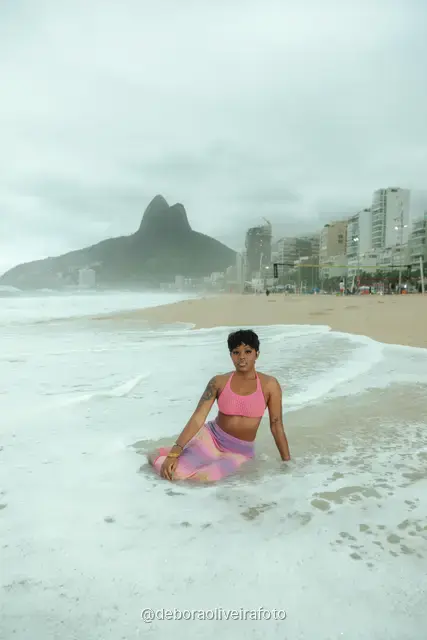 Woman in a pink crochet set on Ipanema Beach with the Two Brothers mountain behind