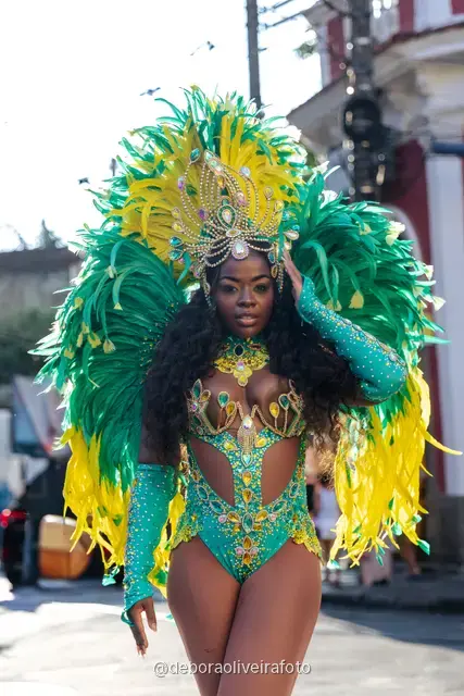 Mujer con disfraz de Carnaval de plumas verdes y amarillas junto al tranvía amarillo en Santa Teresa, Río de Janeiro