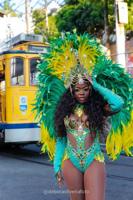Woman in a green and yellow feather Carnival costume next to the yellow tram in Santa Teresa, Rio de Janeiro