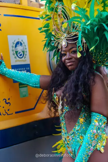Mujer con disfraz de Carnaval de plumas verdes y amarillas junto al tranvía amarillo en Santa Teresa, Río de Janeiro