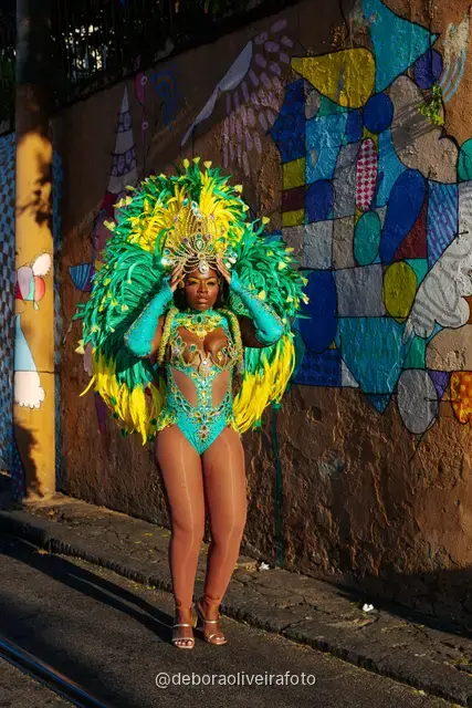 Mujer con disfraz de Carnaval de plumas verdes y amarillas junto al tranvía amarillo en Santa Teresa, Río de Janeiro