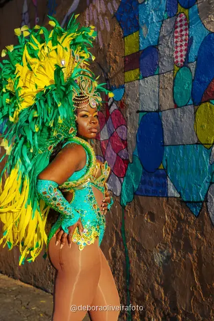 Mujer con disfraz de Carnaval de plumas verdes y amarillas junto al tranvía amarillo en Santa Teresa, Río de Janeiro