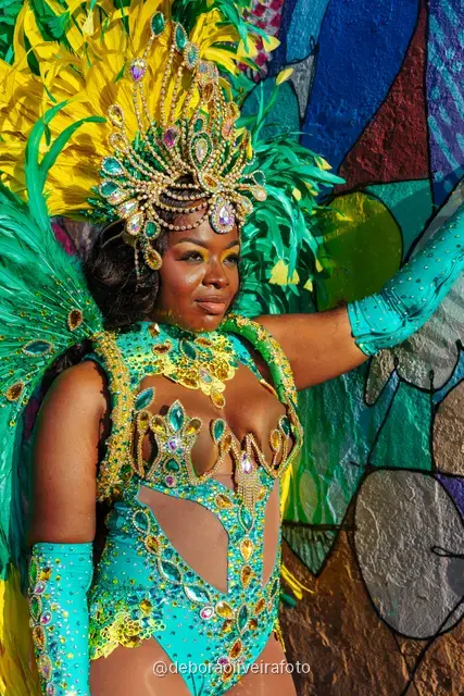 Woman in a green and yellow feather Carnival costume next to the yellow tram in Santa Teresa, Rio de Janeiro