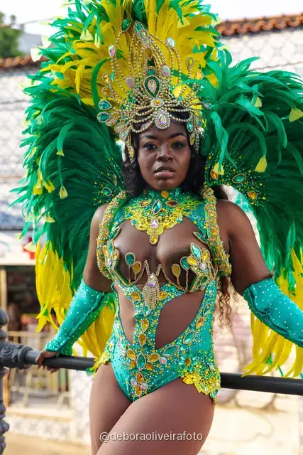 Mujer con disfraz de Carnaval de plumas verdes y amarillas junto al tranvía amarillo en Santa Teresa, Río de Janeiro