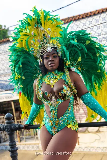 Mujer con disfraz de Carnaval de plumas verdes y amarillas junto al tranvía amarillo en Santa Teresa, Río de Janeiro