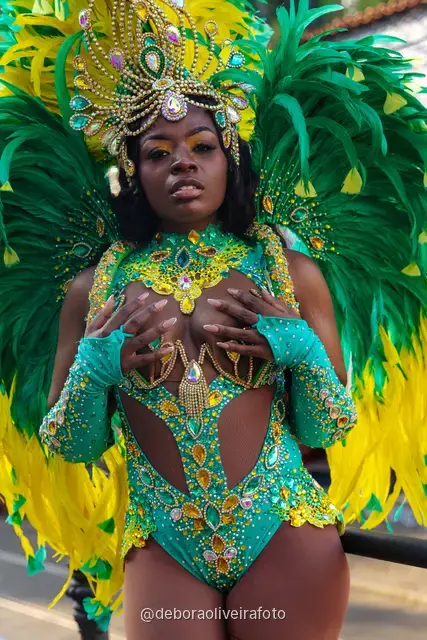 Retrato de cerca de un disfraz de Carnaval con plumas y tocado de pedrería frente a un mural colorido en Santa Teresa