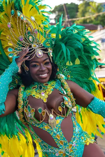 Close portrait of a Carnival costume with feathers and beaded headdress in front of a colorful mural in Santa Teresa