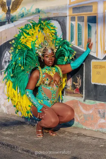 Close portrait of a Carnival costume with feathers and beaded headdress in front of a colorful mural in Santa Teresa