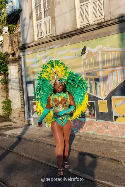 Retrato de cerca de un disfraz de Carnaval con plumas y tocado de pedrería frente a un mural colorido en Santa Teresa