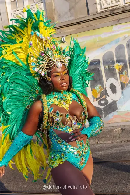 Retrato de cerca de un disfraz de Carnaval con plumas y tocado de pedrería frente a un mural colorido en Santa Teresa