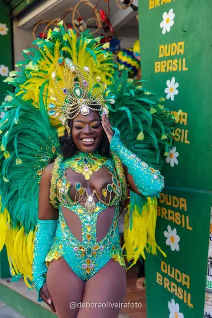 Mujer con disfraz de Carnaval caminando por la calle en Santa Teresa frente a una pared verde y un mural con el tranvía y el Pan de Azúcar