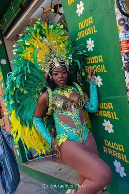 Mujer con disfraz de Carnaval caminando por la calle en Santa Teresa frente a una pared verde y un mural con el tranvía y el Pan de Azúcar