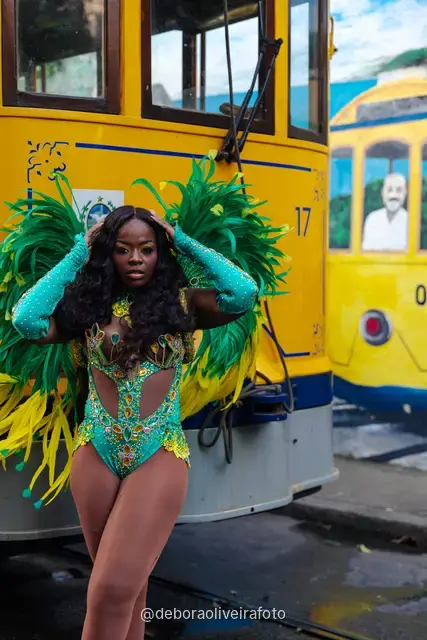 Mujer con disfraz de Carnaval caminando por la calle en Santa Teresa frente a una pared verde y un mural con el tranvía y el Pan de Azúcar