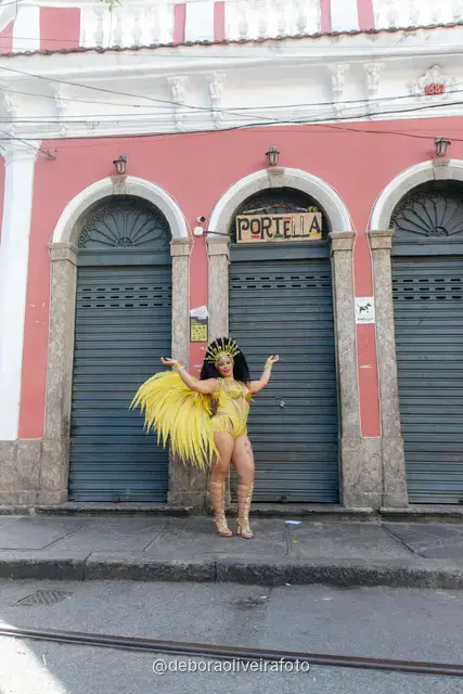 Mujer con disfraz de samba de plumas amarillas y doradas en los rieles del tranvía de Santa Teresa, en Río de Janeiro