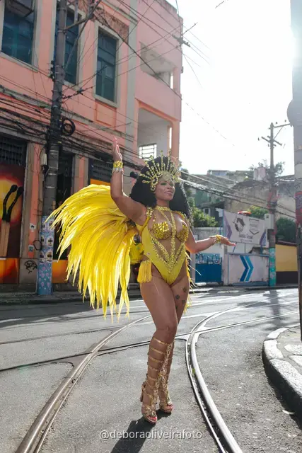 Mujer con disfraz de samba de plumas amarillas y doradas en los rieles del tranvía de Santa Teresa, en Río de Janeiro