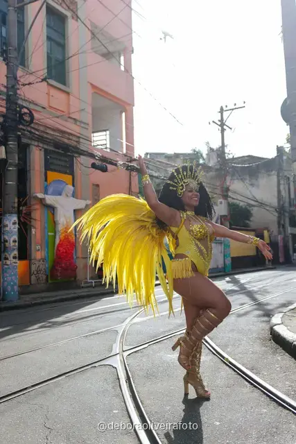 Mujer con disfraz de samba de plumas amarillas y doradas en los rieles del tranvía de Santa Teresa, en Río de Janeiro