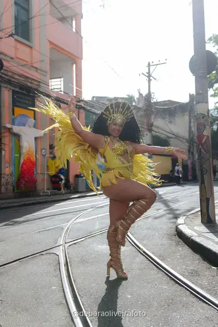 Mujer con disfraz de samba de plumas amarillas y doradas en los rieles del tranvía de Santa Teresa, en Río de Janeiro