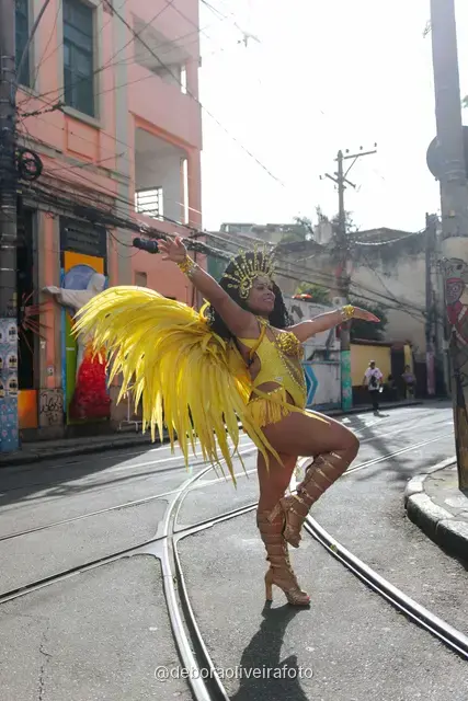 Mujer con disfraz de samba de plumas amarillas y doradas en los rieles del tranvía de Santa Teresa, en Río de Janeiro
