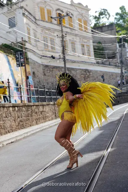 Mujer con disfraz de samba de plumas amarillas y doradas en los rieles del tranvía de Santa Teresa, en Río de Janeiro
