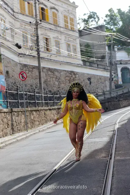 Mujer con disfraz de samba de plumas amarillas y doradas en los rieles del tranvía de Santa Teresa, en Río de Janeiro