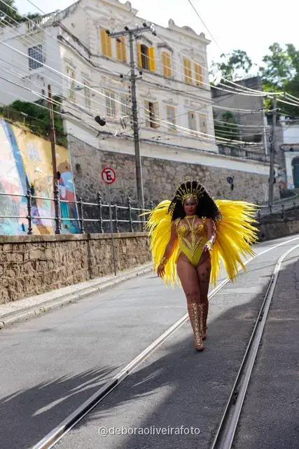Mujer con disfraz de samba de plumas amarillas y doradas en los rieles del tranvía de Santa Teresa, en Río de Janeiro
