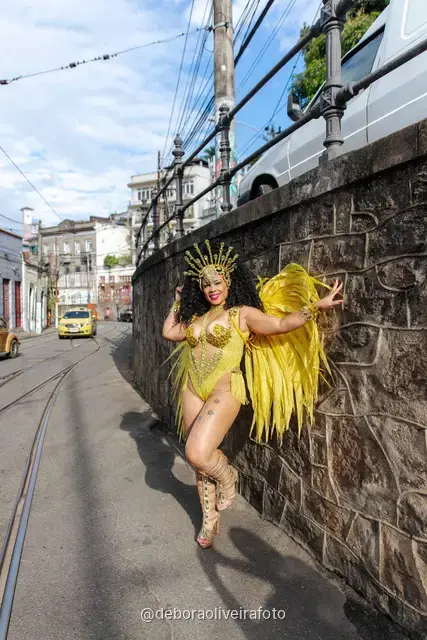 Mujer con disfraz de samba de plumas amarillas y doradas en los rieles del tranvía de Santa Teresa, en Río de Janeiro