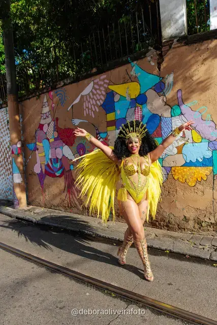 Mujer con disfraz de samba de plumas amarillas y doradas en los rieles del tranvía de Santa Teresa, en Río de Janeiro