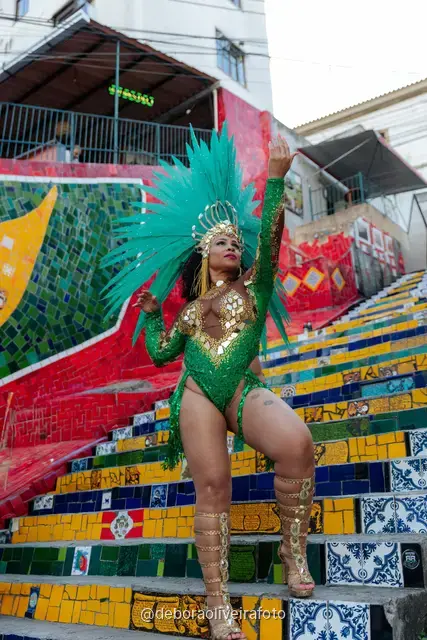 Mujer con look verde de lentejuelas y tocado de plumas turquesa en la Escalinata Selarón y las paredes de azulejos rojos, en Río de Janeiro