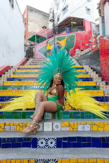 Mujer con look verde de lentejuelas y tocado de plumas turquesa en la Escalinata Selarón y las paredes de azulejos rojos, en Río de Janeiro