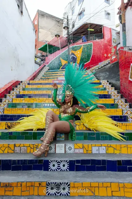 Mujer con look verde de lentejuelas y tocado de plumas turquesa en la Escalinata Selarón y las paredes de azulejos rojos, en Río de Janeiro