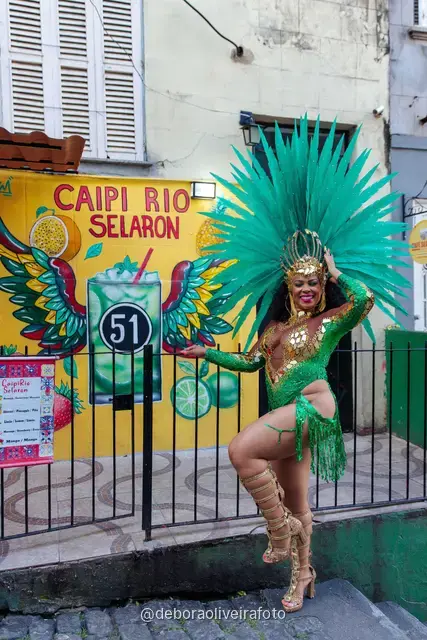 Mujer con look verde de lentejuelas y tocado de plumas turquesa en la Escalinata Selarón y las paredes de azulejos rojos, en Río de Janeiro