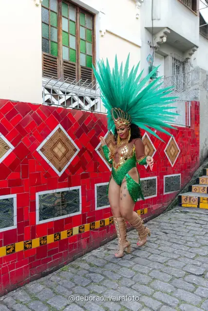 Mujer con look verde de lentejuelas y tocado de plumas turquesa en la Escalinata Selarón y las paredes de azulejos rojos, en Río de Janeiro