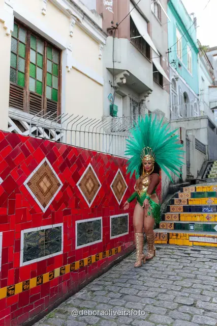 Mujer con look verde de lentejuelas y tocado de plumas turquesa en la Escalinata Selarón y las paredes de azulejos rojos, en Río de Janeiro
