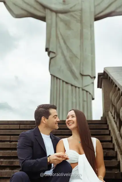 Couple sitting close on the steps below the Christ the Redeemer statue in Rio de Janeiro