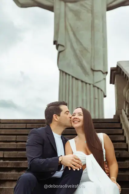 Couple sitting close on the steps below the Christ the Redeemer statue in Rio de Janeiro