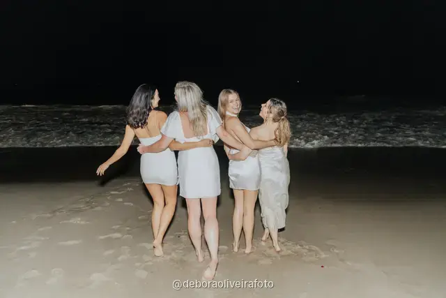 Grupo de mulheres de branco correndo nas ondas da praia de Copacabana à noite, no Rio de Janeiro