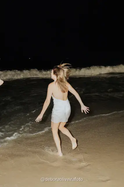 Grupo de mulheres de branco correndo nas ondas da praia de Copacabana à noite, no Rio de Janeiro