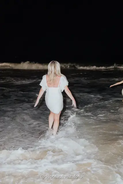 Grupo de mulheres de branco correndo nas ondas da praia de Copacabana à noite, no Rio de Janeiro