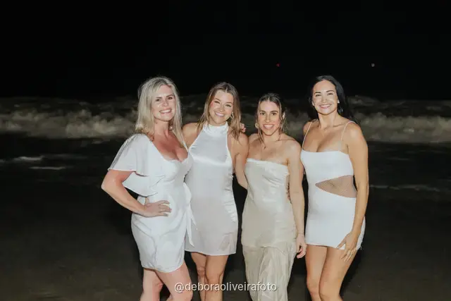 Group of four women in white jumping and posing together at Copacabana Beach at night