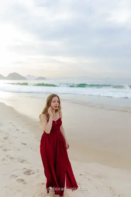Woman in a long red dress with a scarf on Copacabana Beach in Rio de Janeiro