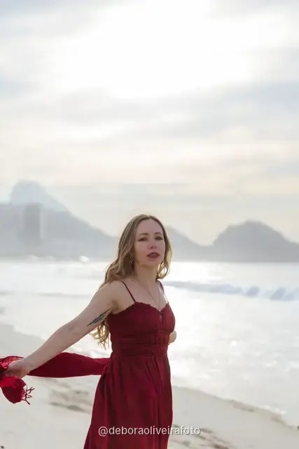 Woman in a long red dress with a scarf on Copacabana Beach in Rio de Janeiro