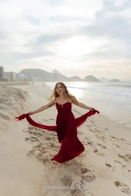 Woman in a long red dress with a scarf on Copacabana Beach in Rio de Janeiro