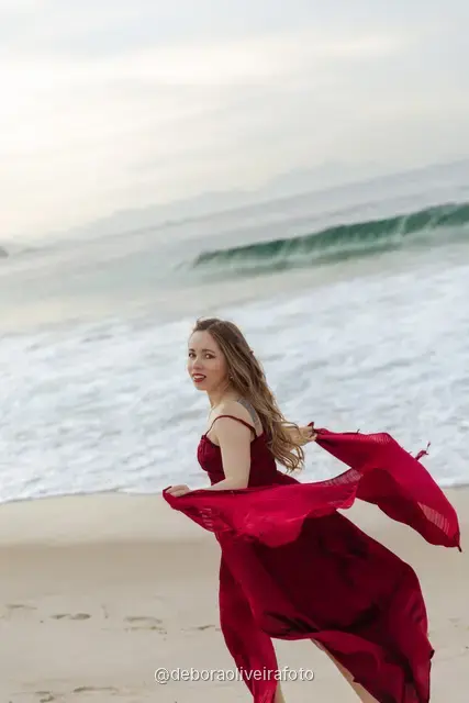 Woman in a long red dress with a scarf on Copacabana Beach in Rio de Janeiro