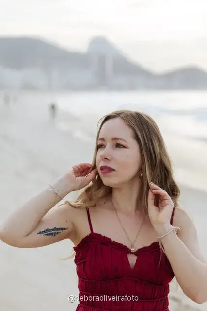 Woman in a long red dress with a scarf on Copacabana Beach in Rio de Janeiro