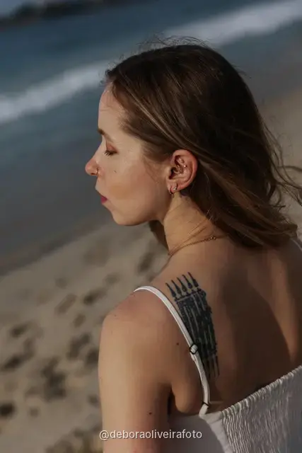Woman in a white lace dress and green jacket sitting on the sand of Copacabana Beach