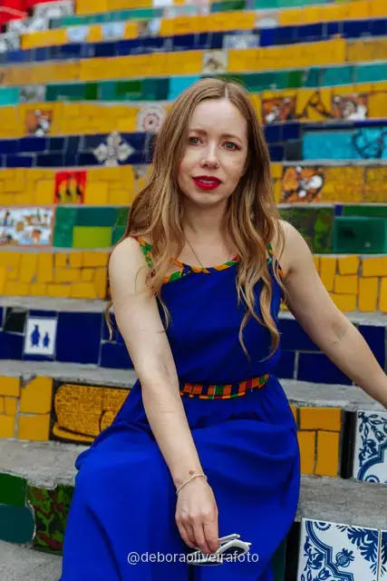 Woman in a blue dress sitting on the colorful tiled Selarón Steps in Santa Teresa, Rio de Janeiro